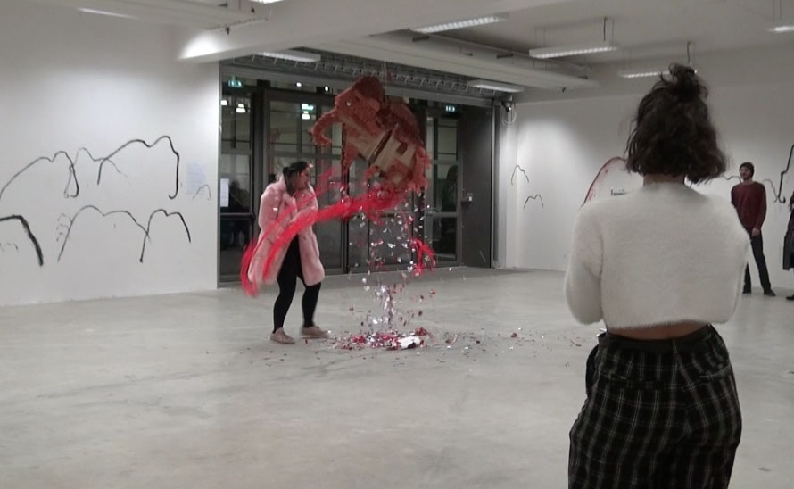 Clélia en manteau de fourrure rose éventre la piñata. Des paillettes et des cotillons rouge en sortent.